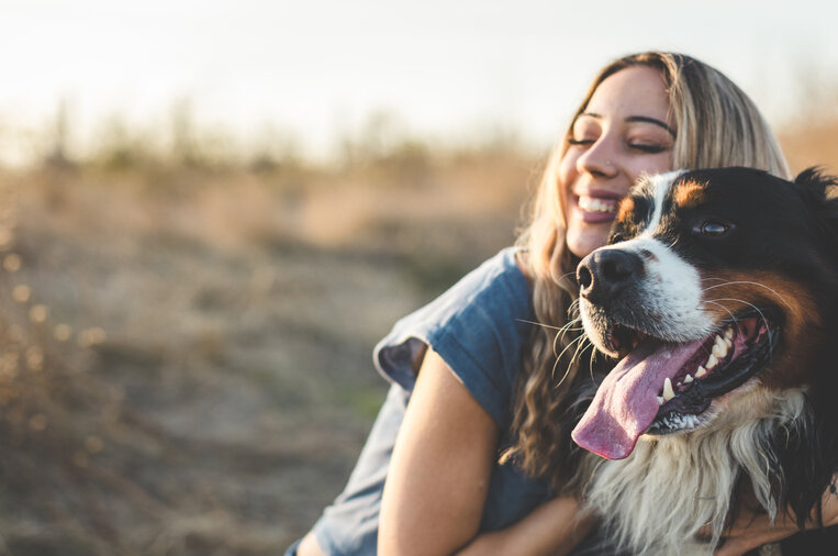 Eine Frau umarmt ihren Hund.