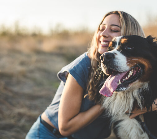 Eine Frau umarmt ihren Hund.